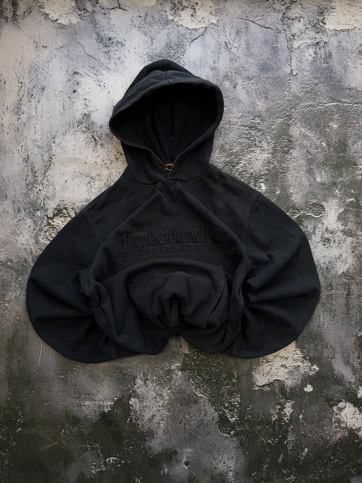 Grafitowa bluza Timberland z haftowanym logo, ułożona na wprost z podwiniętymi rękawami i dołem