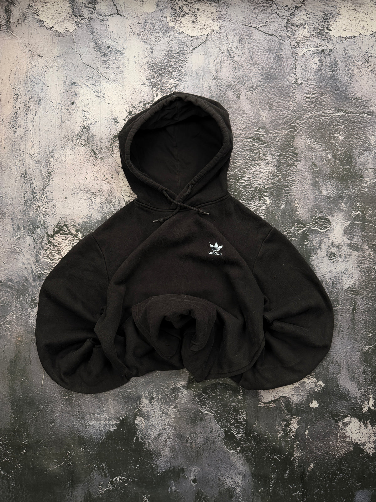 Czarna bluza Adidas Originals z białym logo Trefoil, ułożona na wprost z podwiniętymi rękawami i dołem