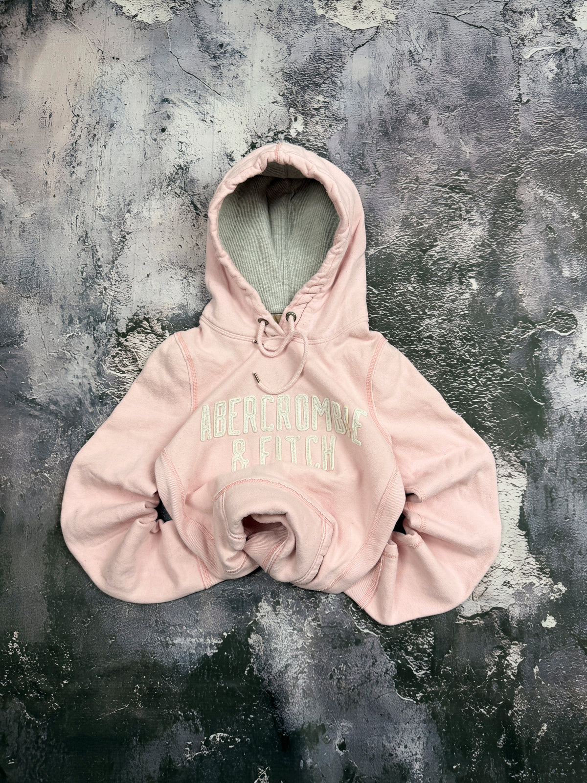 Bluza Abercrombie & Fitch jasnoróżowa z kapturem i miętowymi napisami – krój prosty — centralne