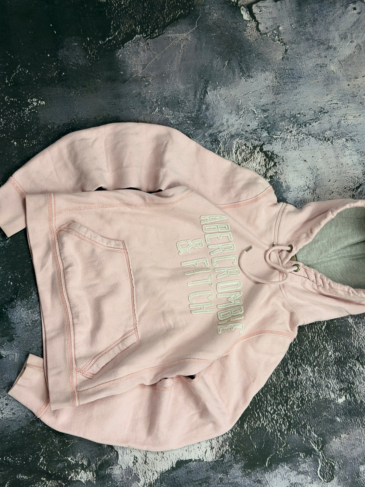Bluza Abercrombie & Fitch jasnoróżowa z kapturem i miętowymi napisami – krój prosty — bok detal napisu